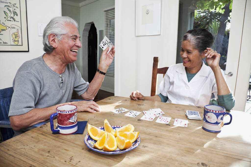 Home nurse and elderly man playing cards